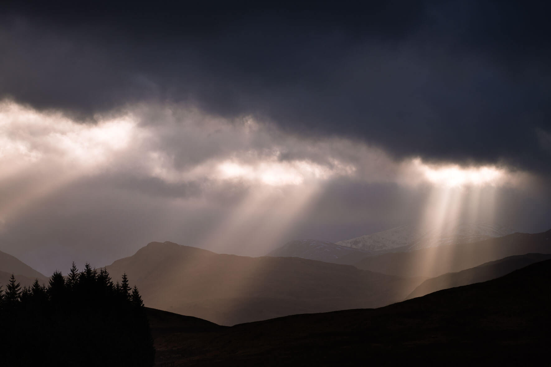 Sun breaking through the dark clouds over Glencoe, Scotland