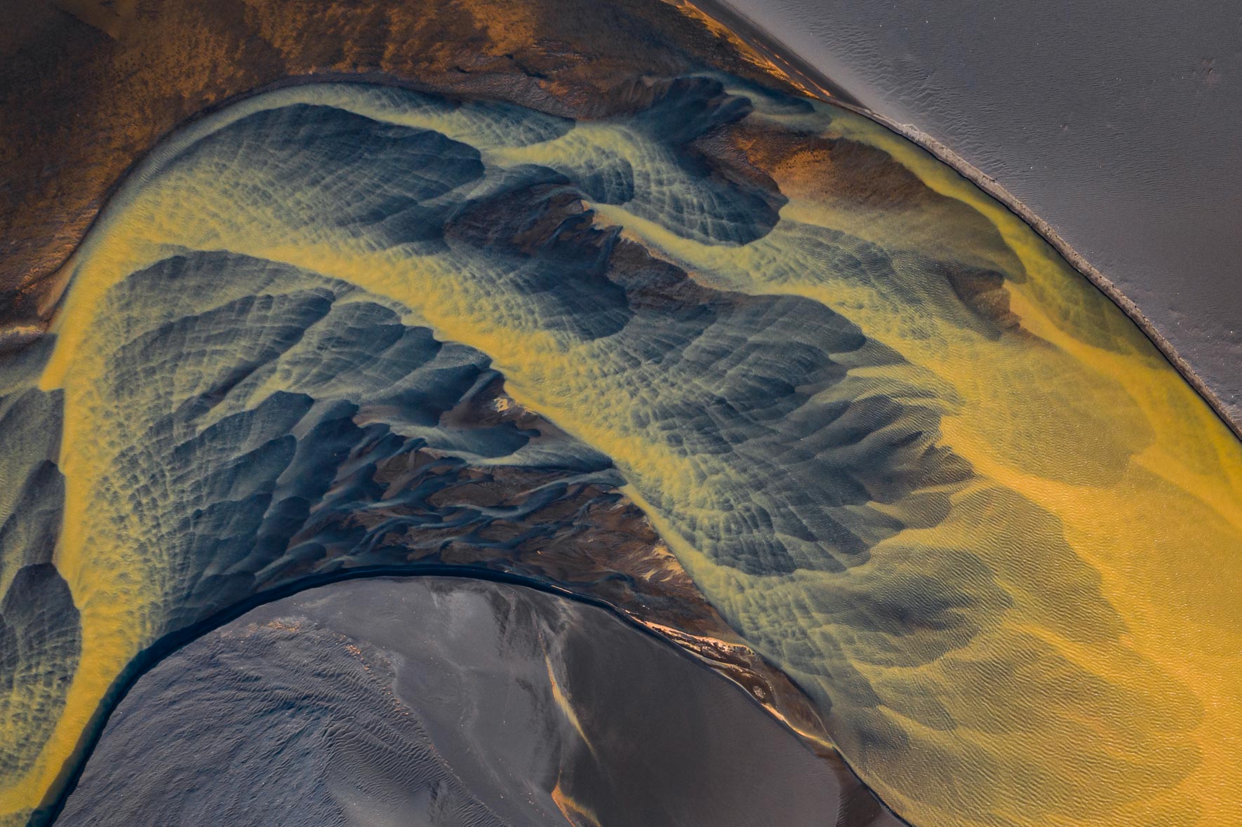 Abstract aerial photograph of colorful glacier river in Iceland with black sand
