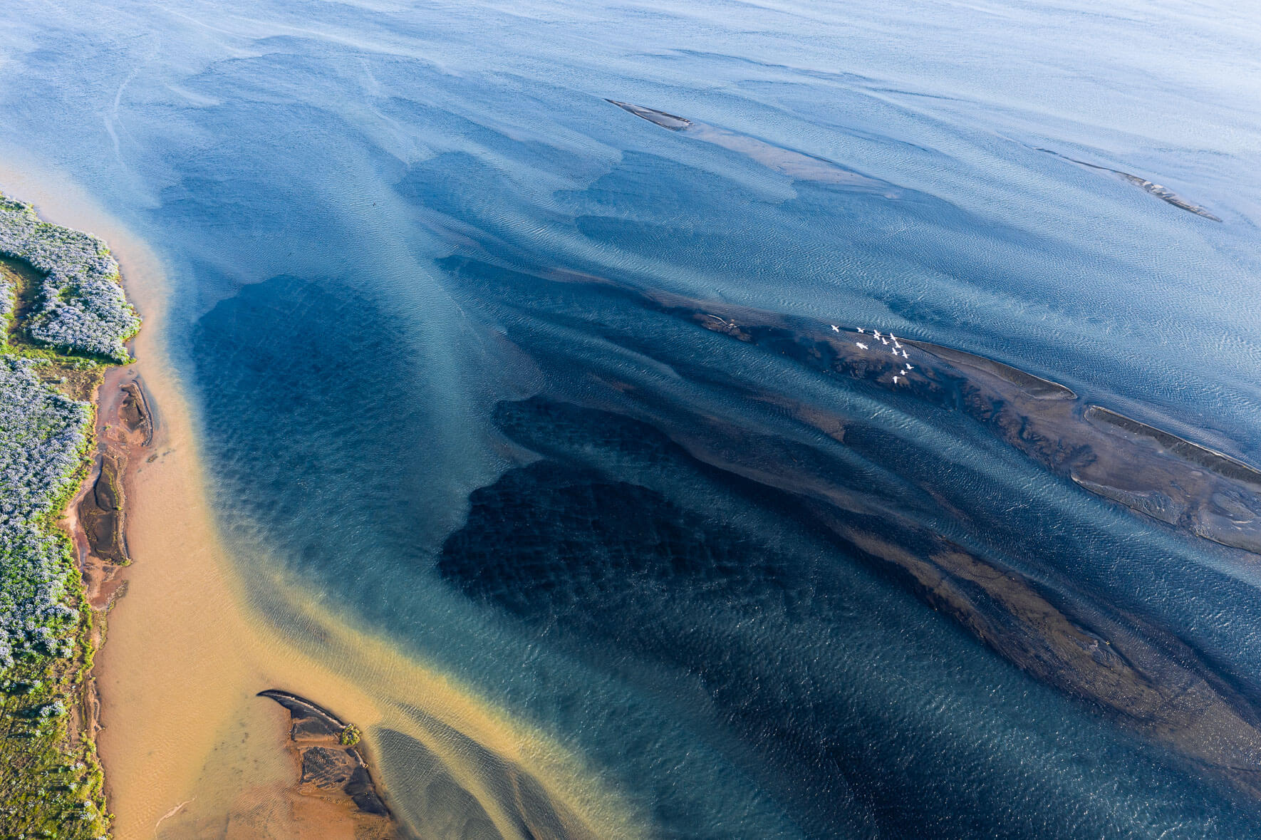 Abstract aerial view of Holsa river in Iceland with small sandbanks and seagulls