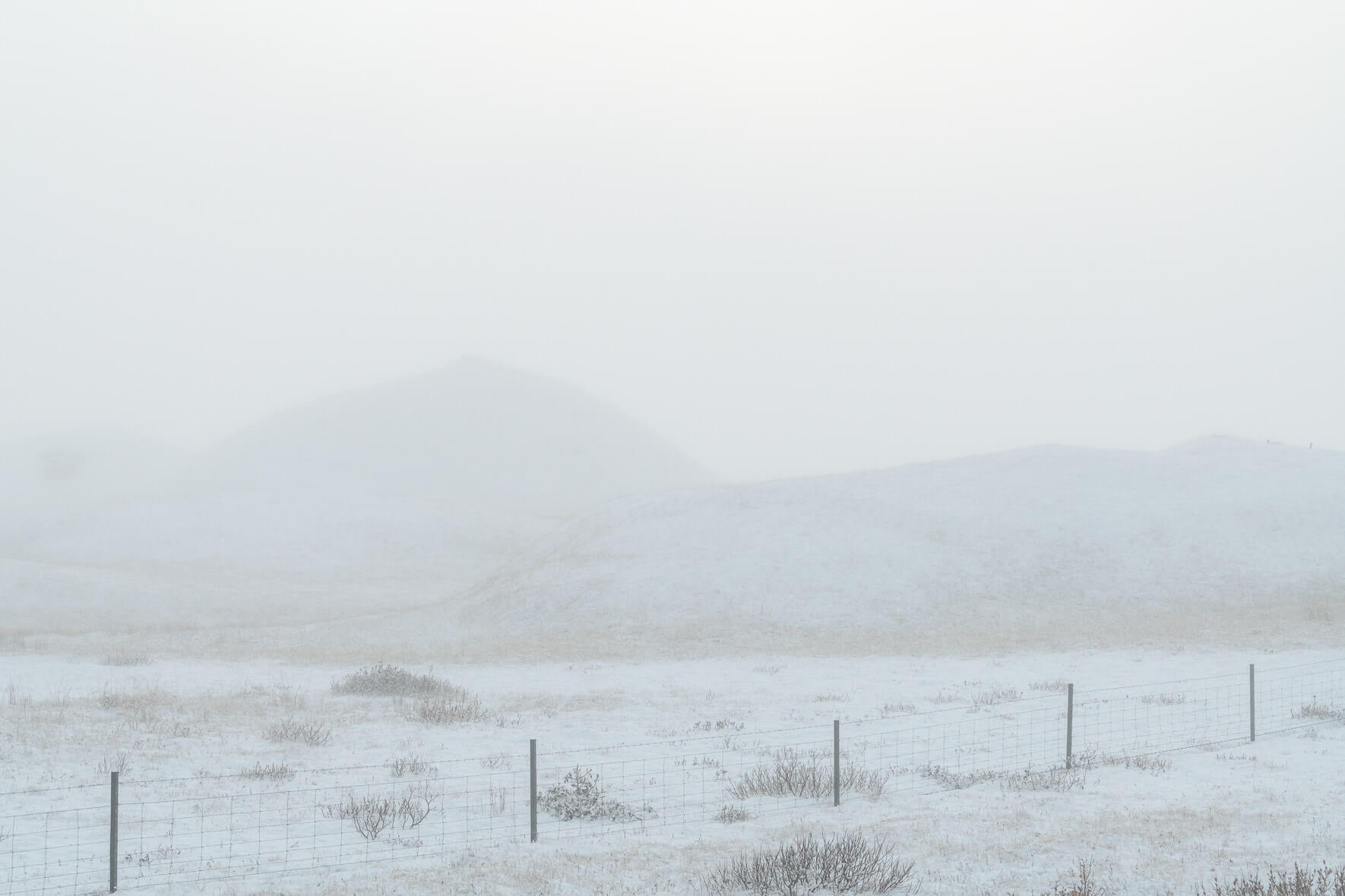 Snow covered hills and fence in winter fog