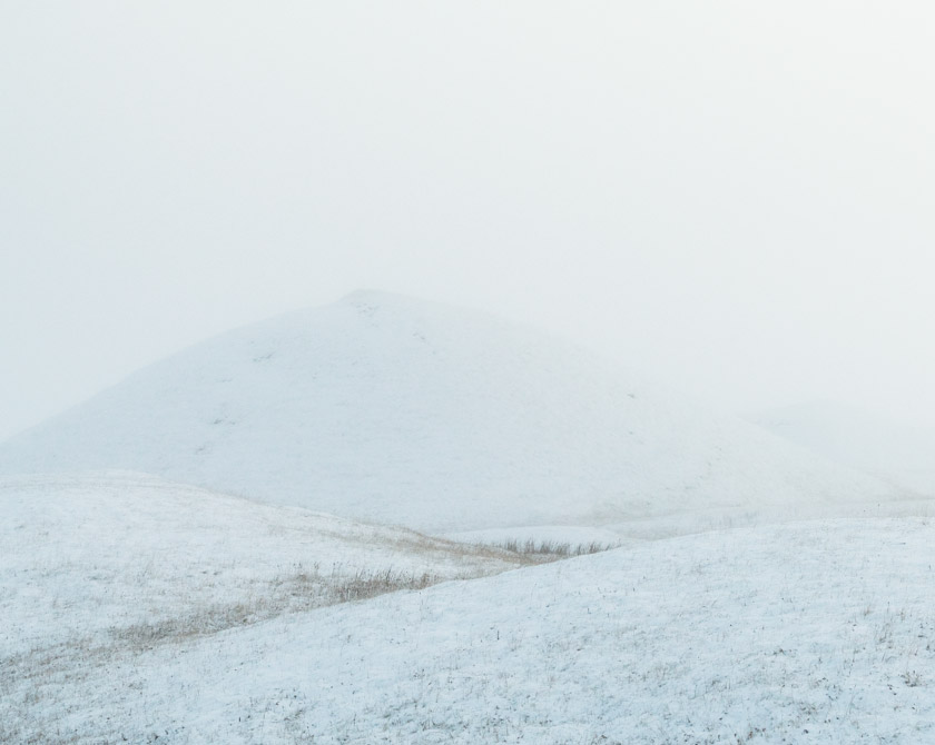 Minimalist scene with snow covered hills in winter fog