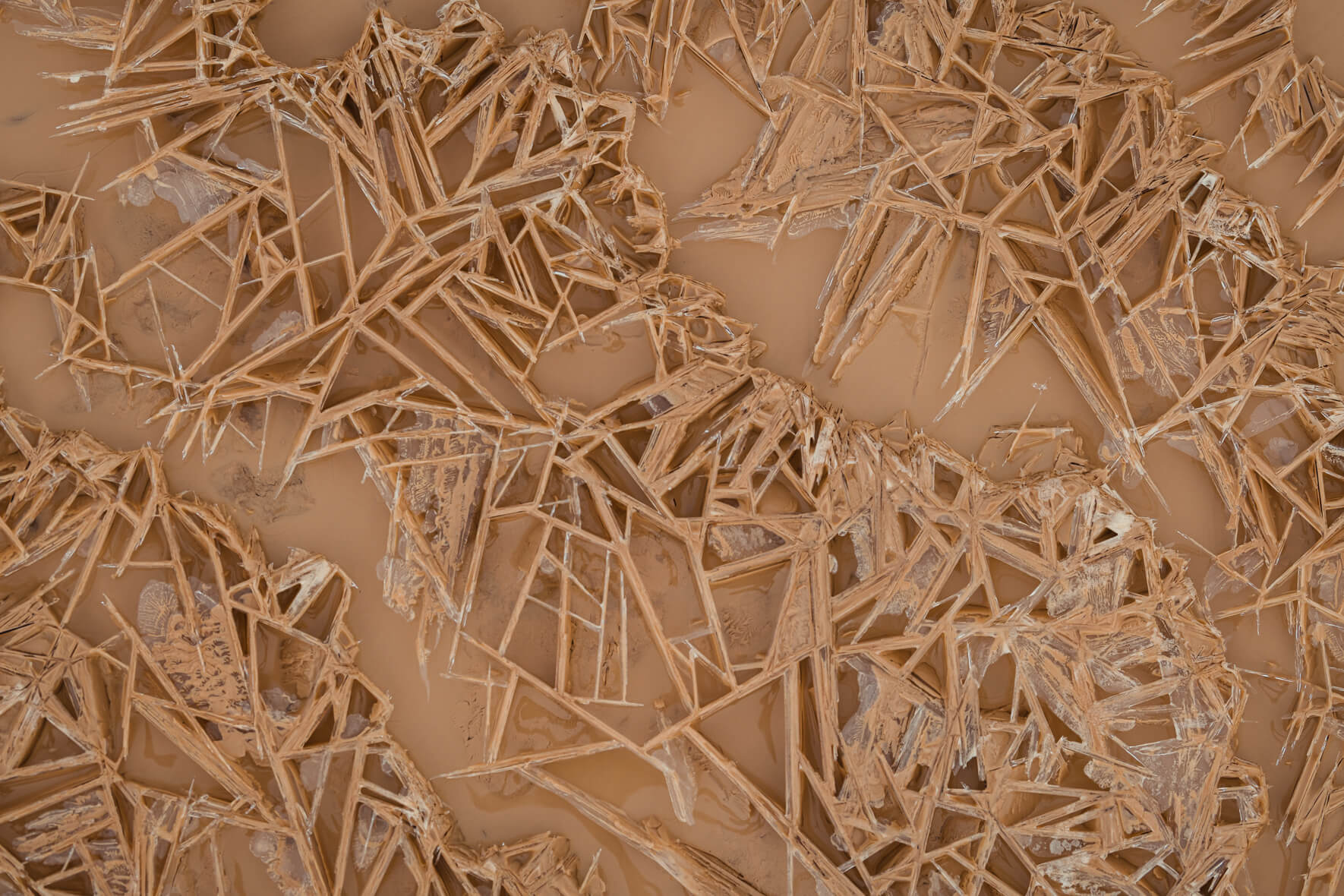 Abstract texture of a frozen and muddy puddle with ice crystals