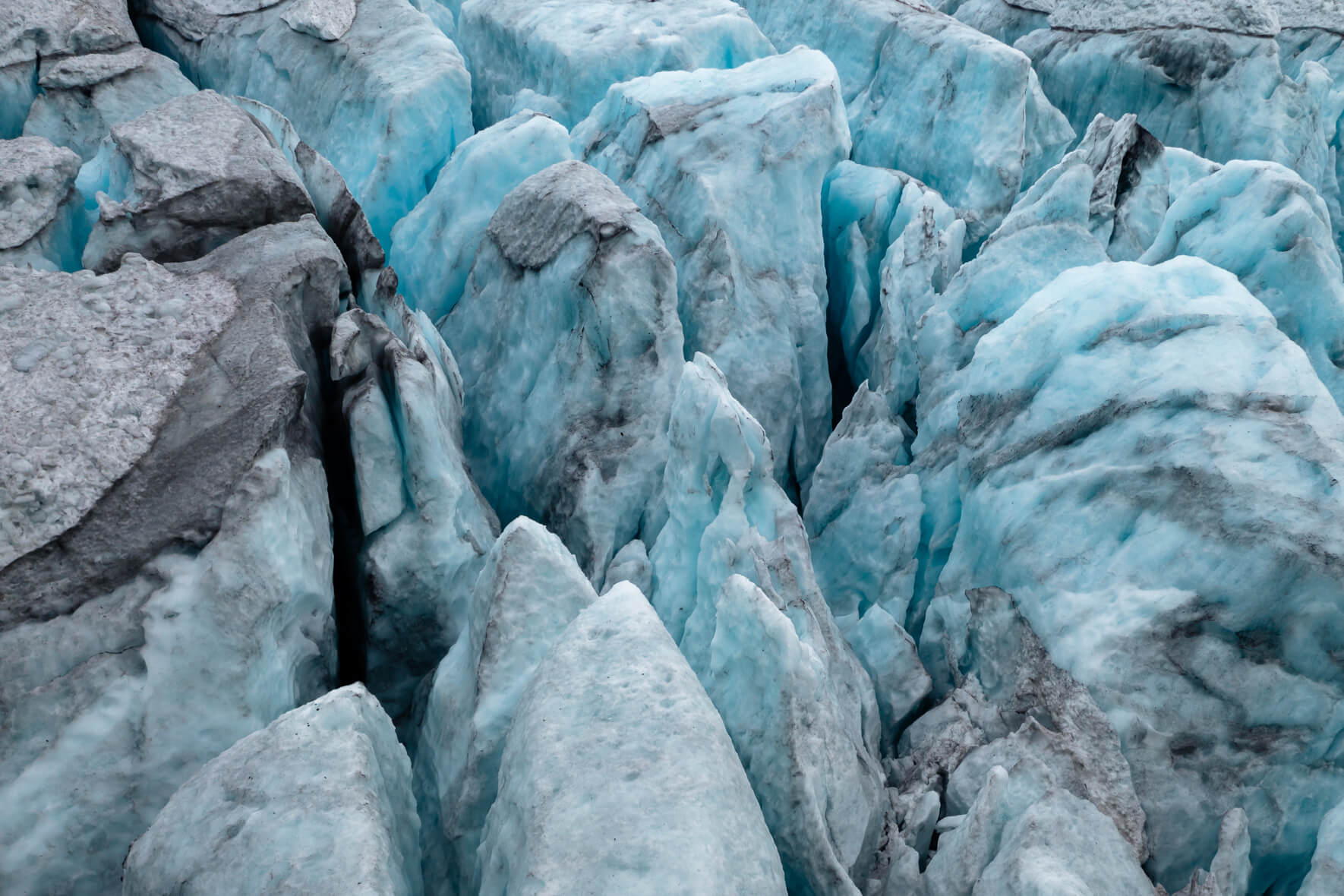 Aerial view of a glacier in Norway with deep crevasses and glowing blue glacier ice