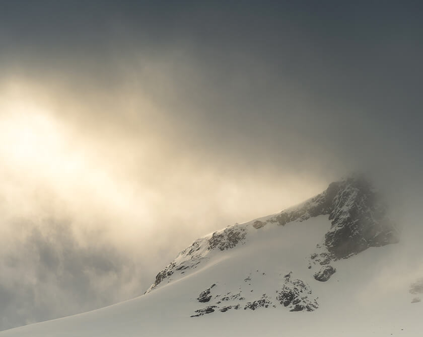 The winter sun breaks through the dark clouds over the Sognefjellet mountains in Norway