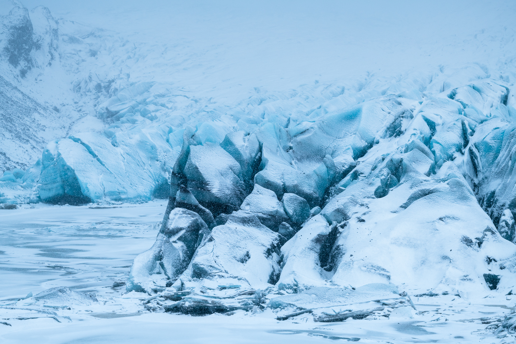 Snow-covered landscape of Svínafellsjökull glacier, surrounded by towering mountains
