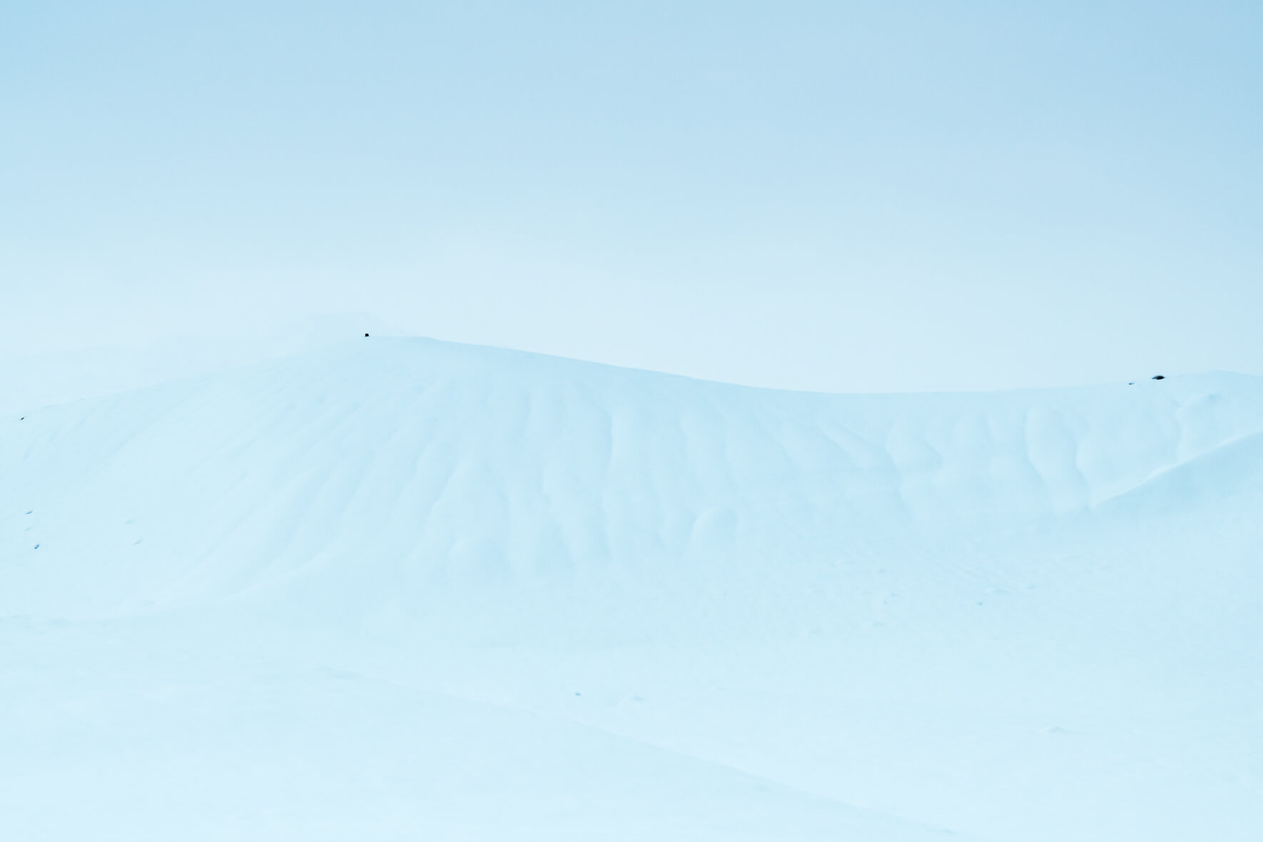 Minimalist winter landscape with a snowy hill and whiteout conditions