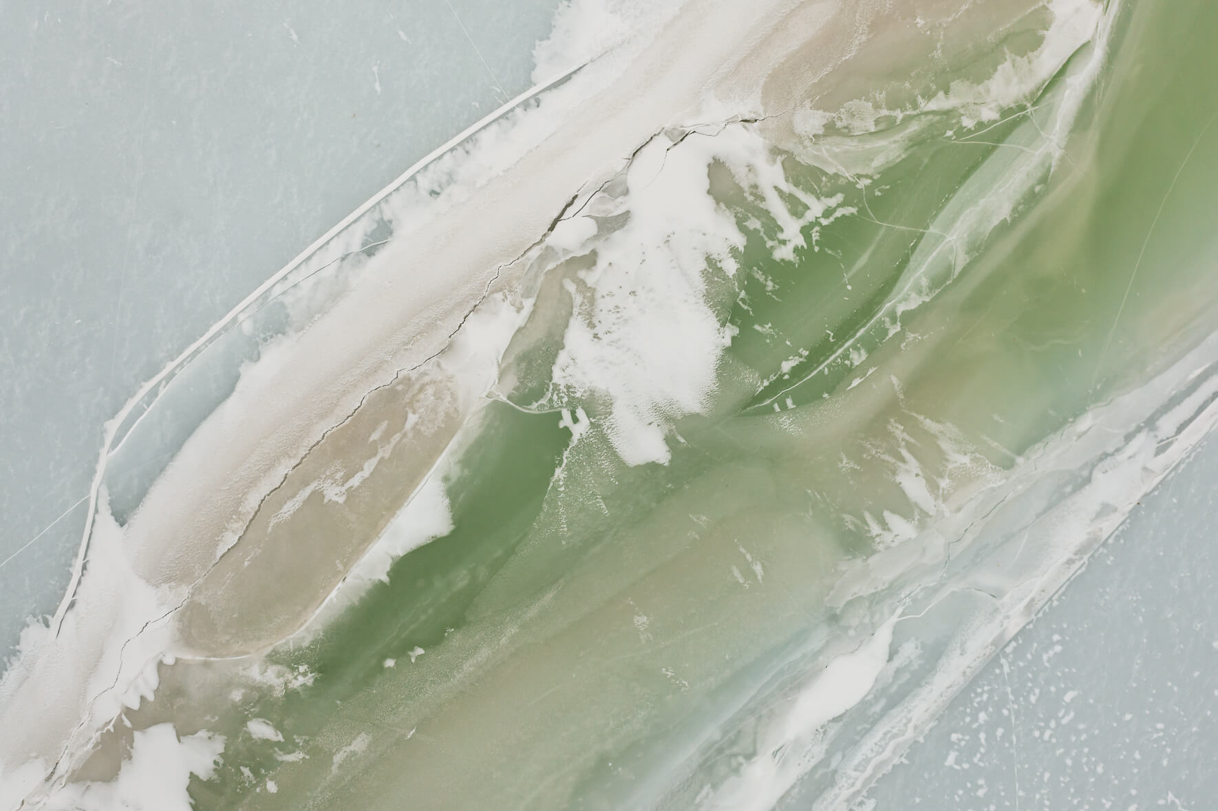 Pastel ice of a frozen lake in Norway with snow remains