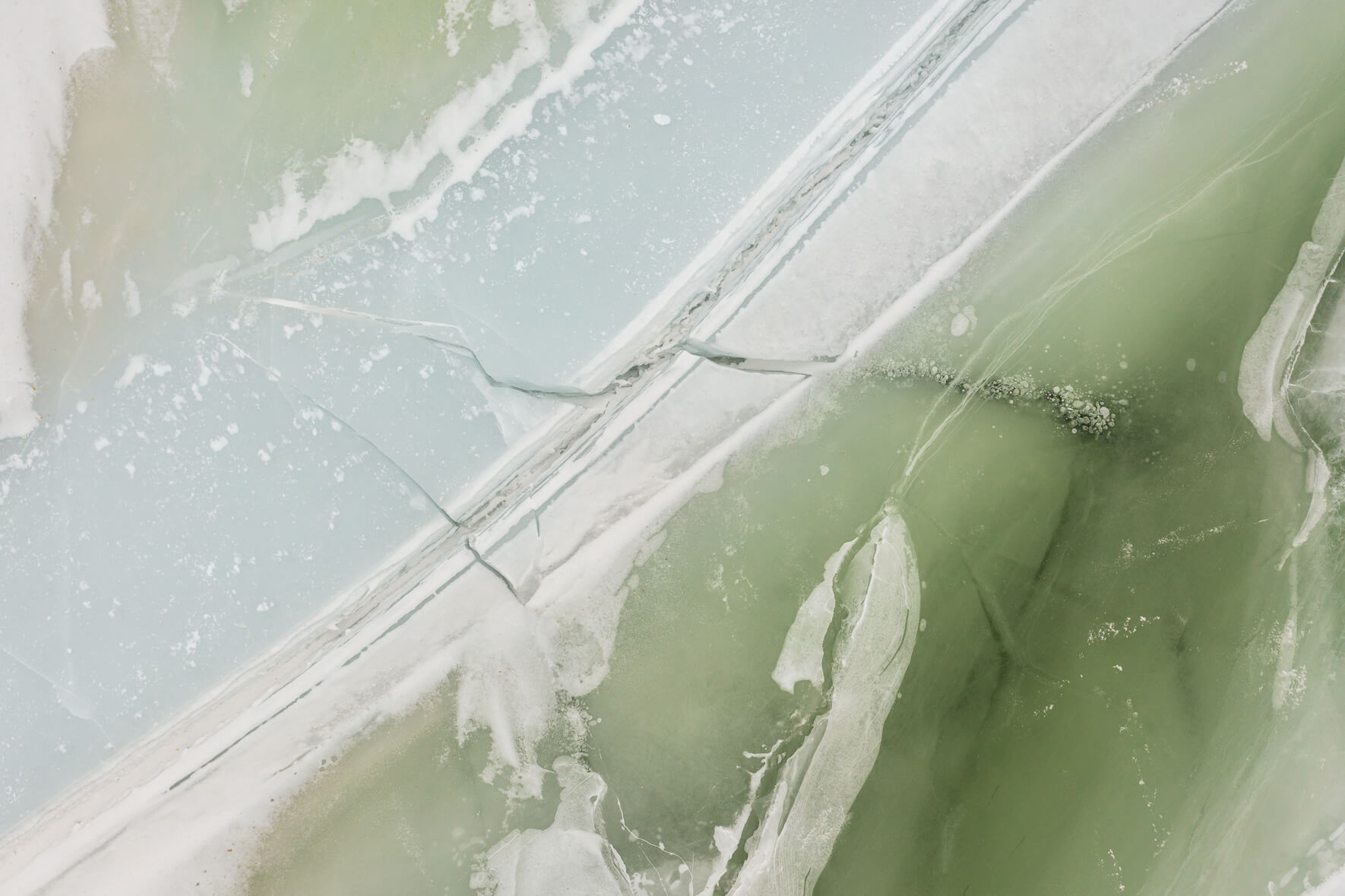 Aerial view of a frozen lake in Norway with pastel colored ice
