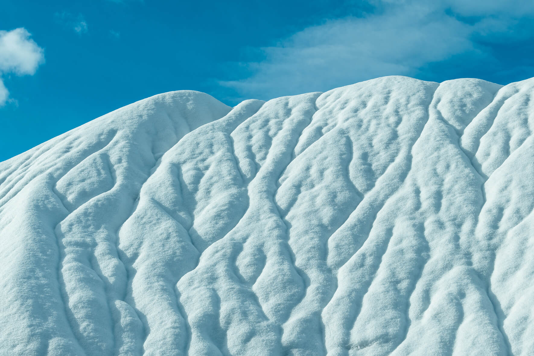Abstract landscape with snow covered hills in a quarry and a blue sky