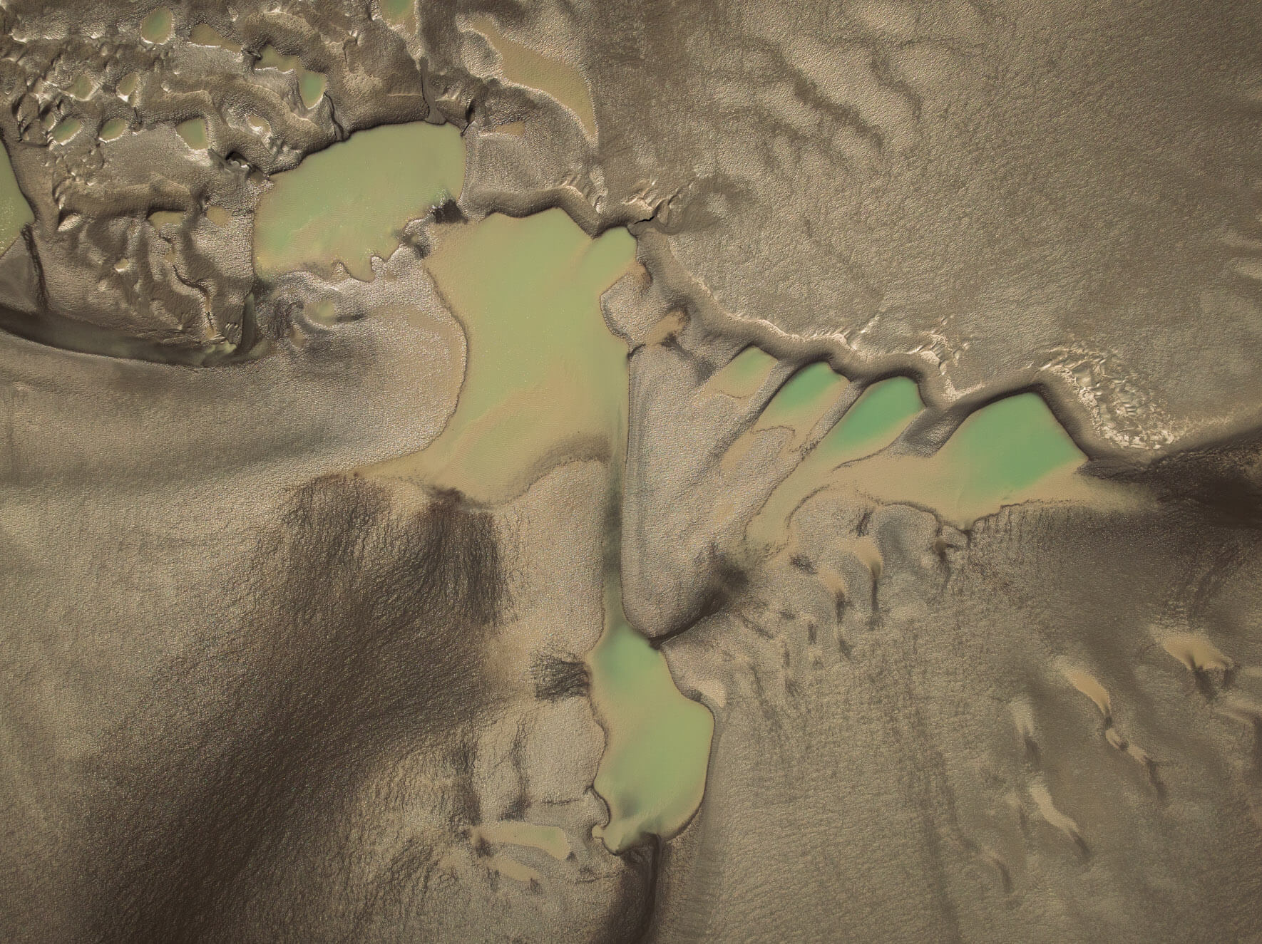 Aerial view of Alaska’s tidal flats showcasing tidal pools and colorful water