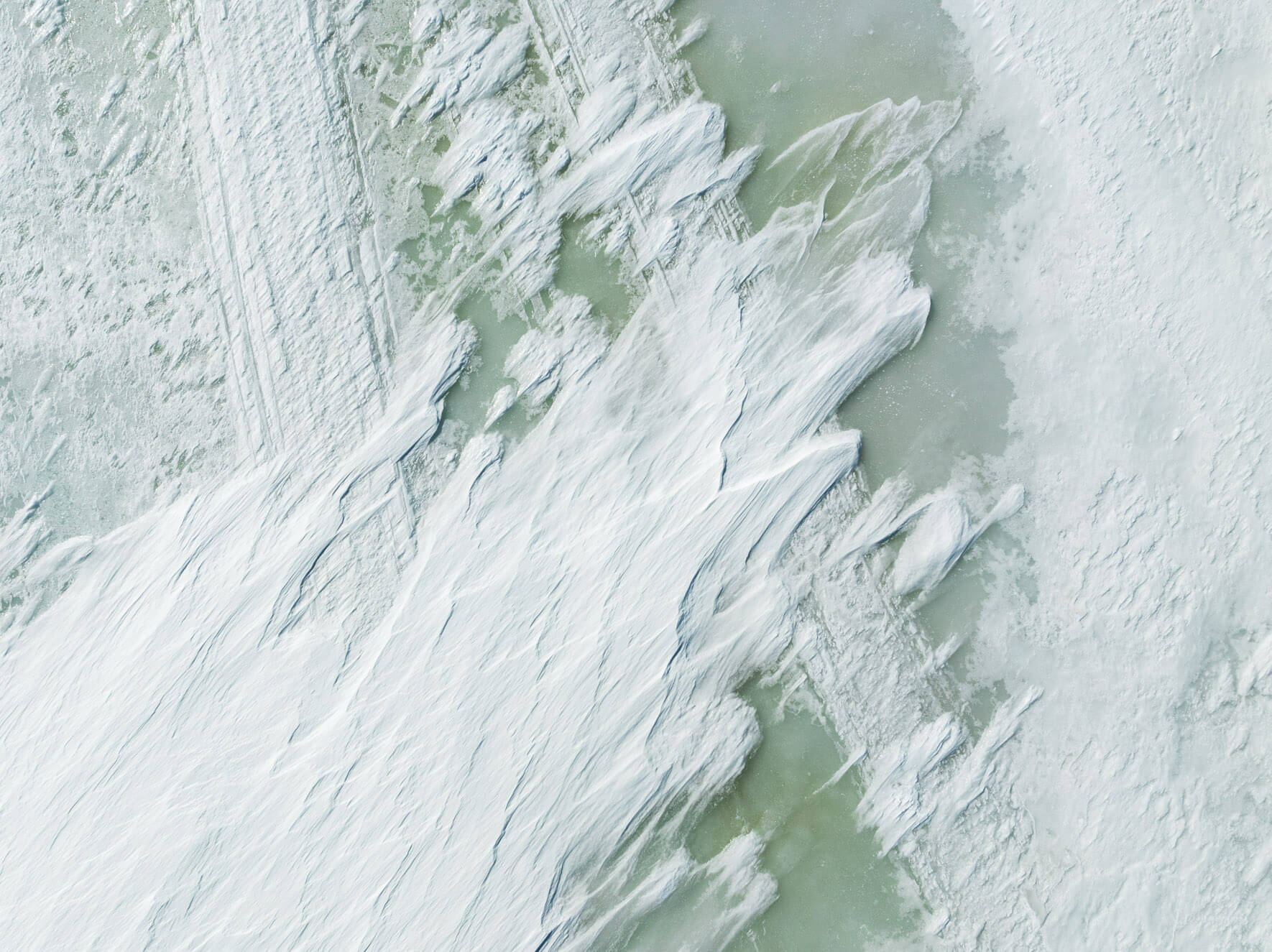 Abstract aerial view of Hardangervidda’s frozen lake showcasing wind-shaped snow patterns