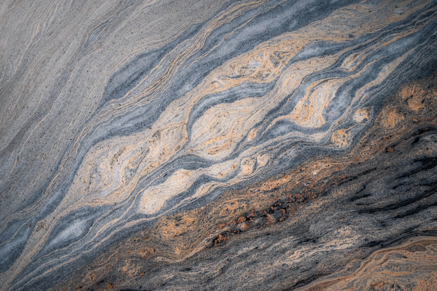 Close-up of organic pollen structures forming flowing patterns in a small stream in Norway