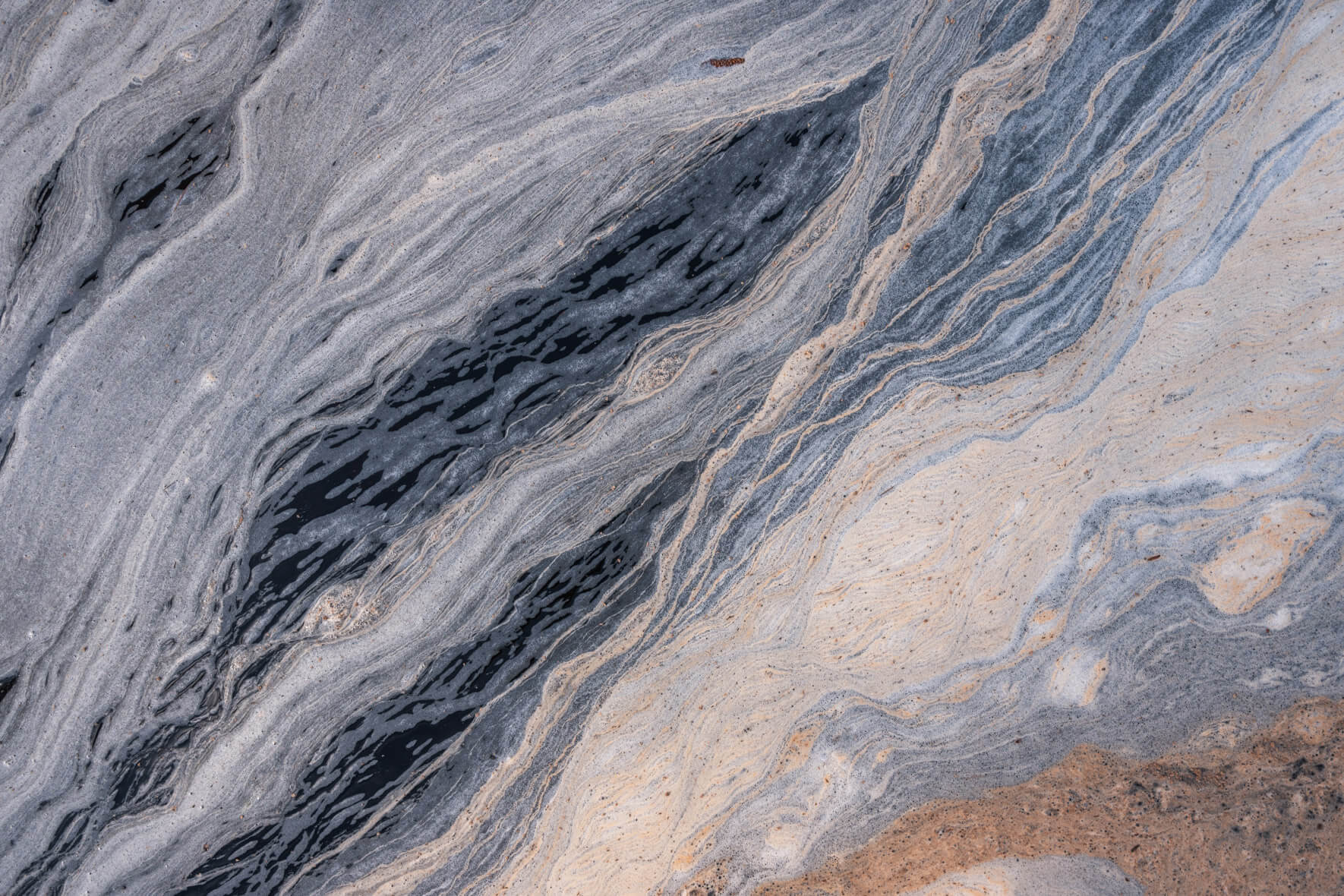 Abstract textures formed by pollen on a stream in Norway resembling Jupiter’s atmosphere