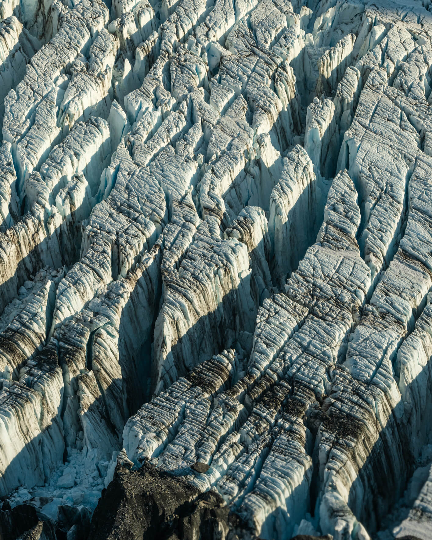 Aerial view of glacier ice walls illuminated by warm Arctic evening light
