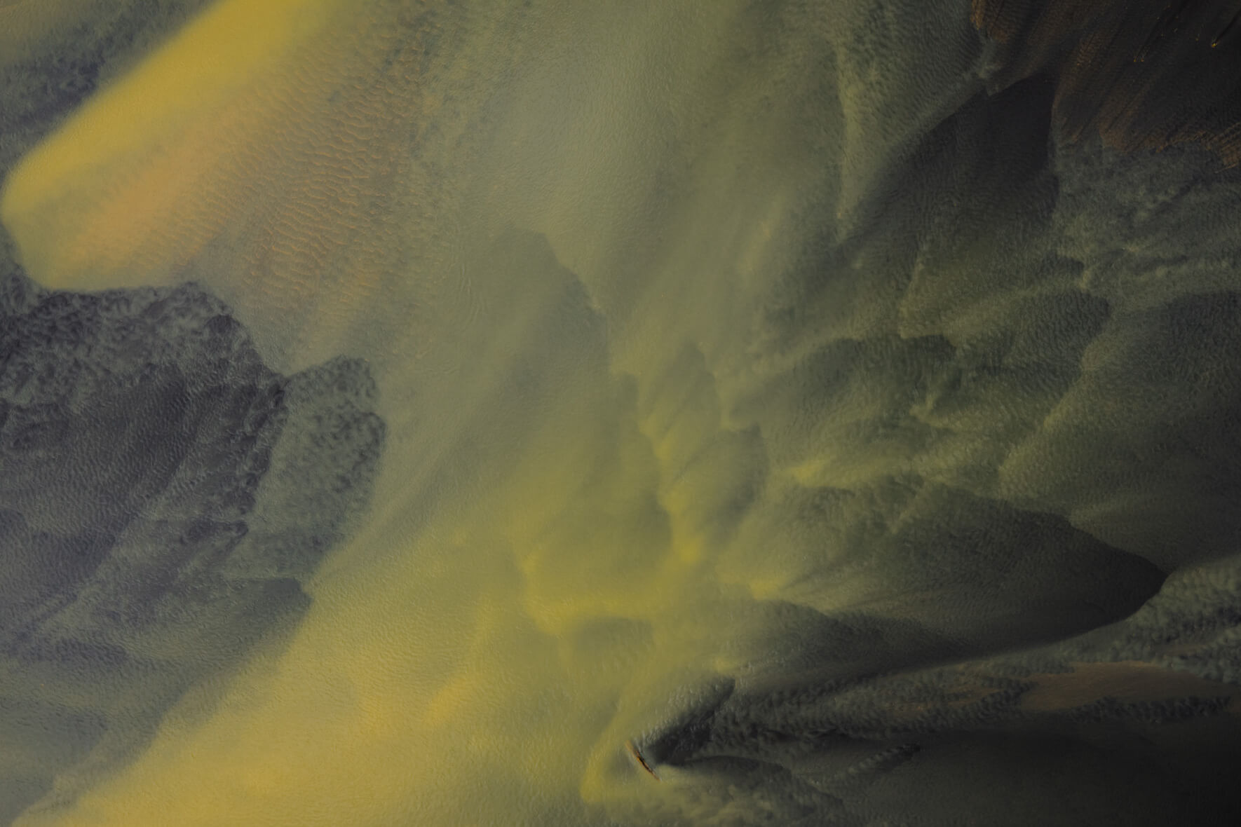 Aerial view of sulphur-stained waterways across dark volcanic plains