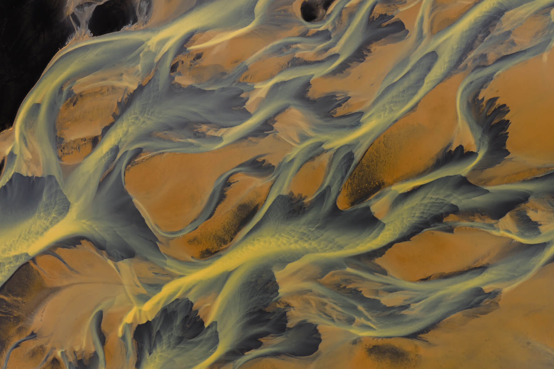 Aerial view of sulphur-rich river delta in Iceland with golden geothermal tones and dark sediment