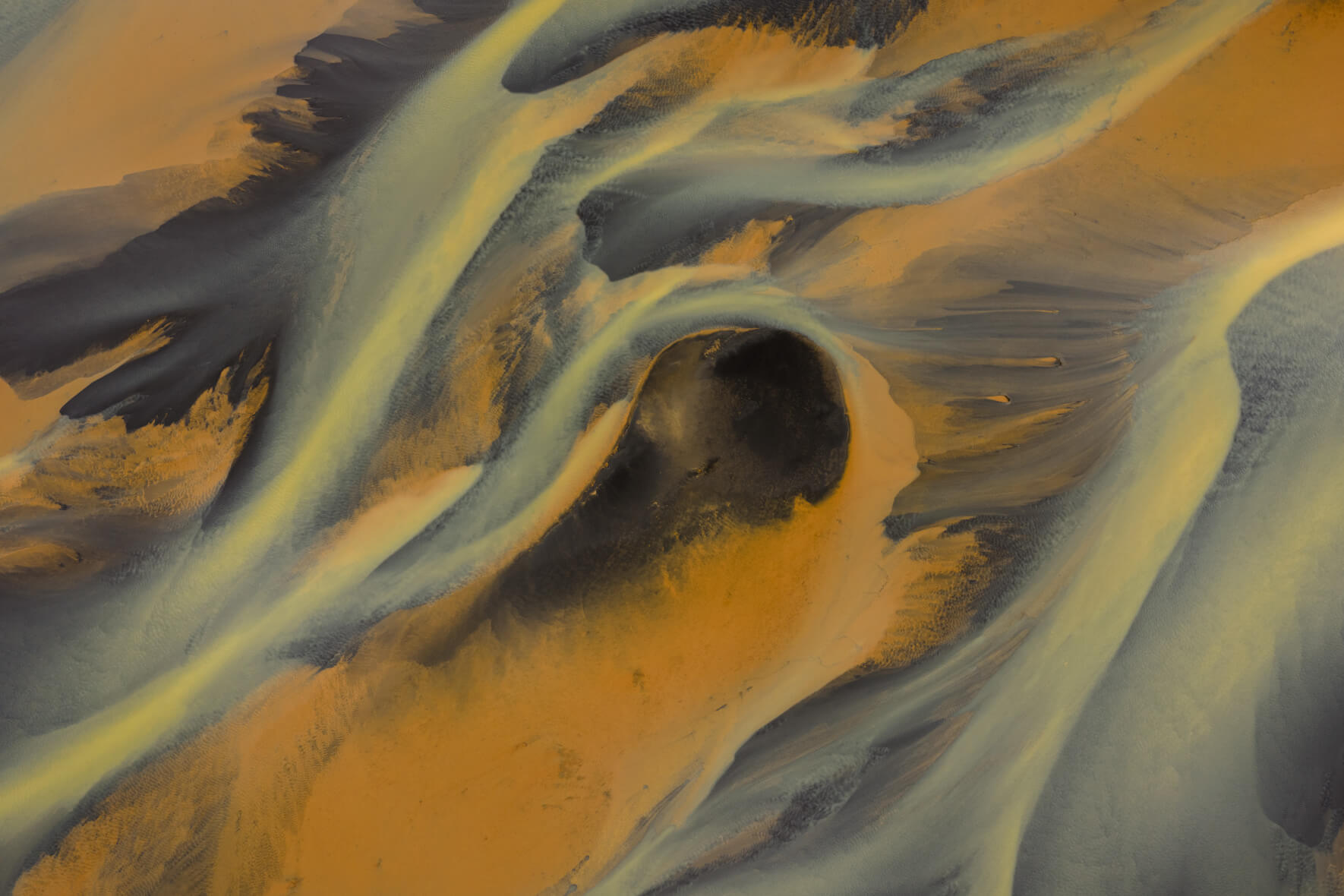 Aerial view of sulphur-rich river delta in Iceland with golden tones and dark sand island