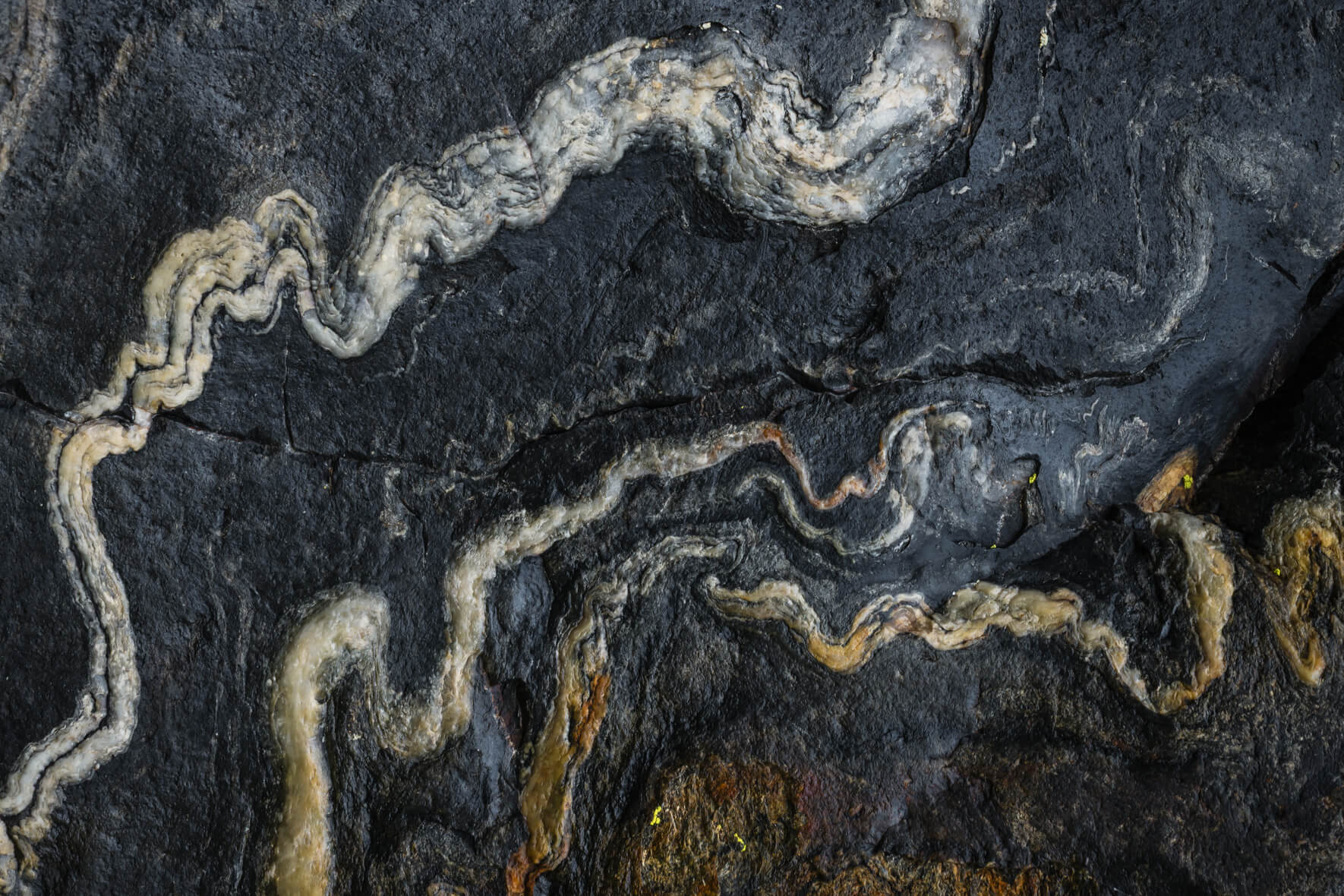 Rock pattern with alternating mineral veins and smooth gray layers