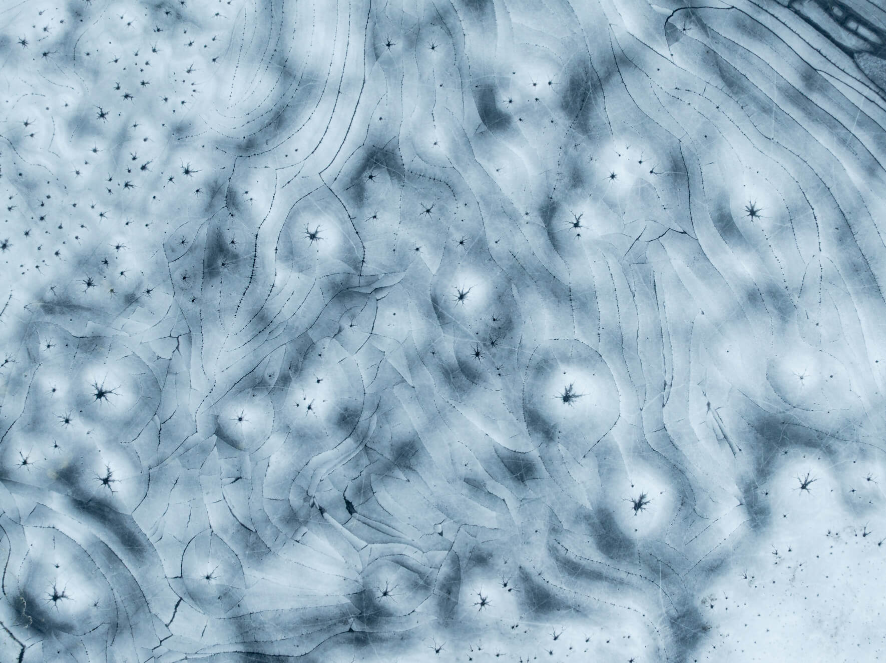 Curved ice formations creating subtle textures across a thawing lake in Norway