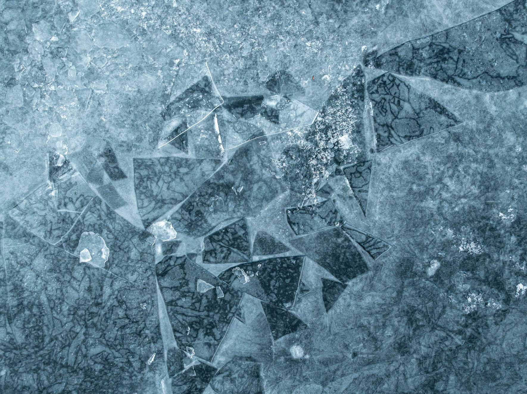 Aerial winter view of frozen lake with abstract shapes and ice layers