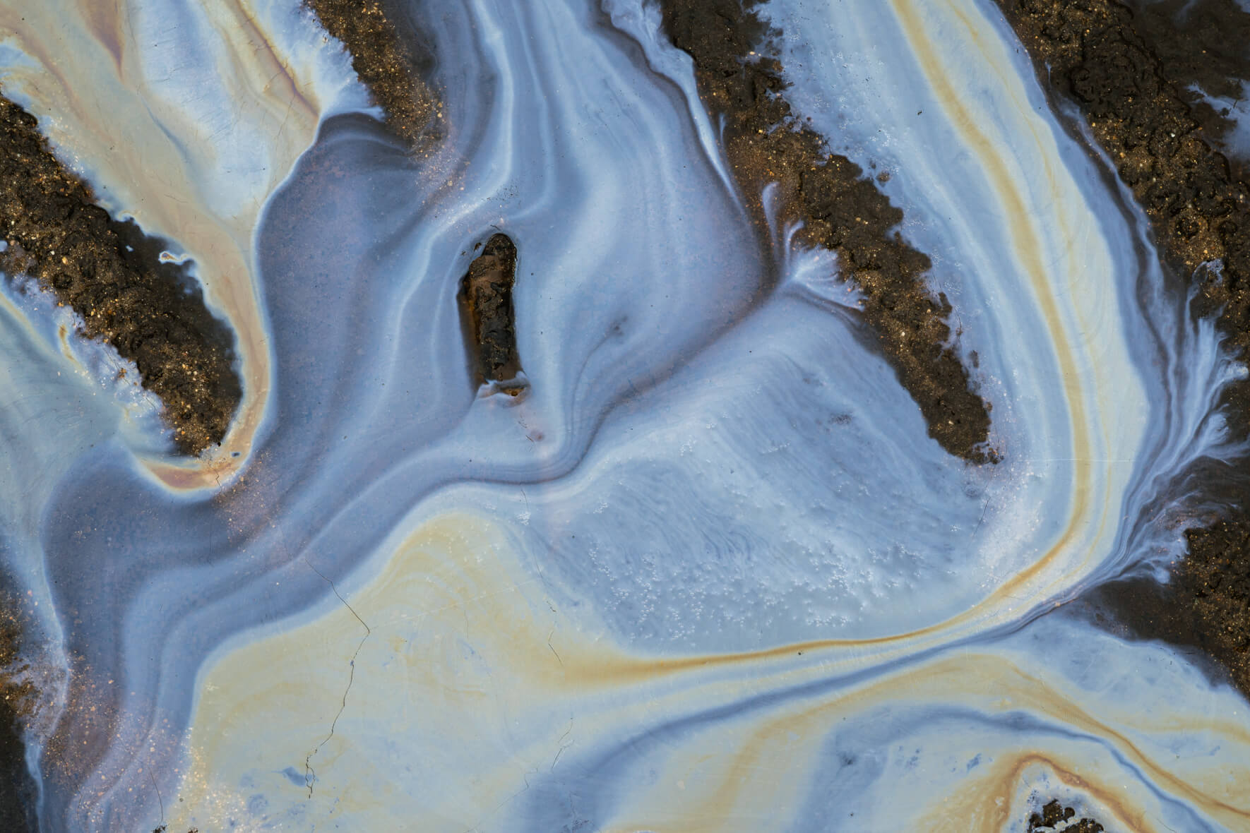 Colorful oxidized layer on shallow water surface showing natural metallic reflections