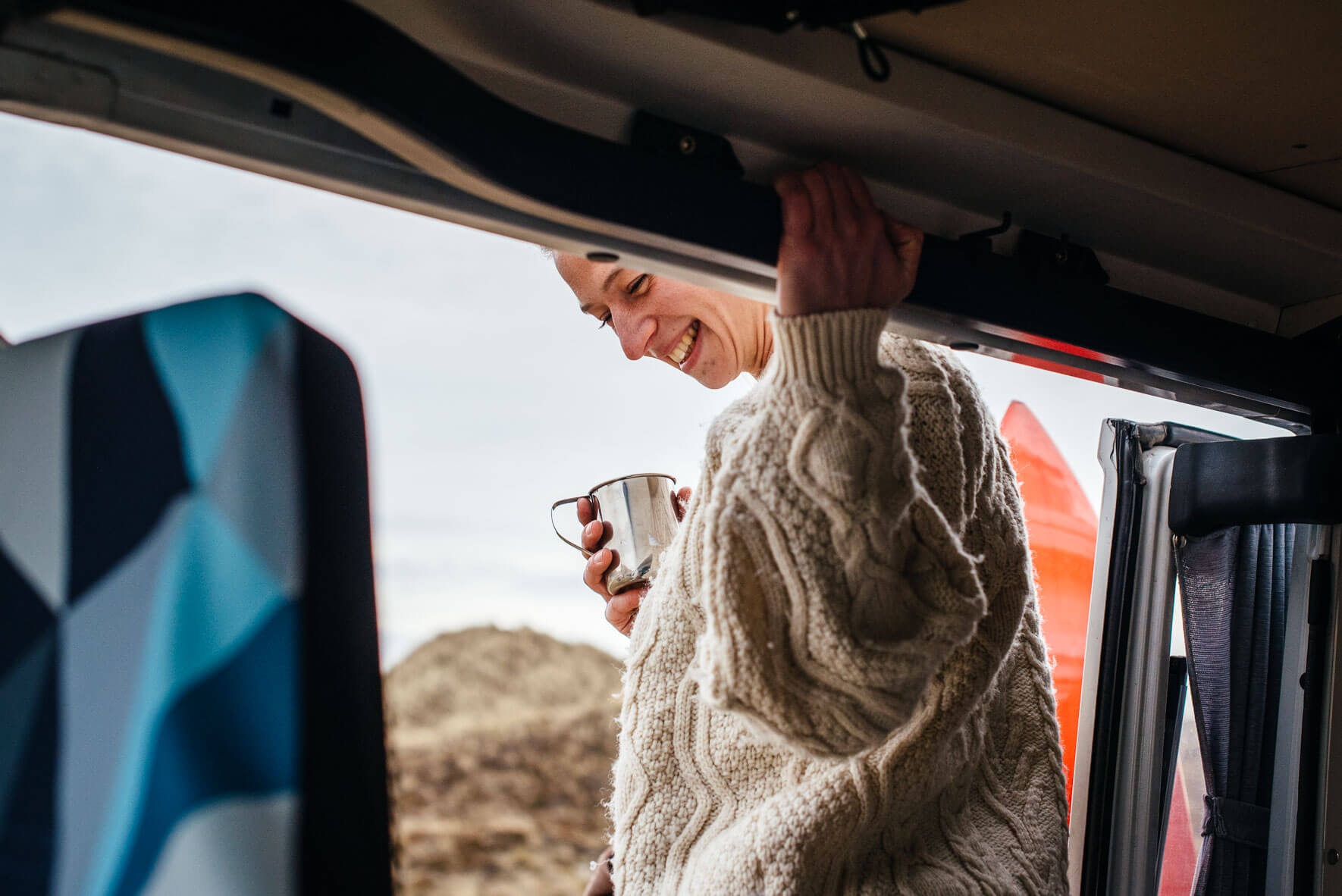 Woman holding a coffee cup in camper van