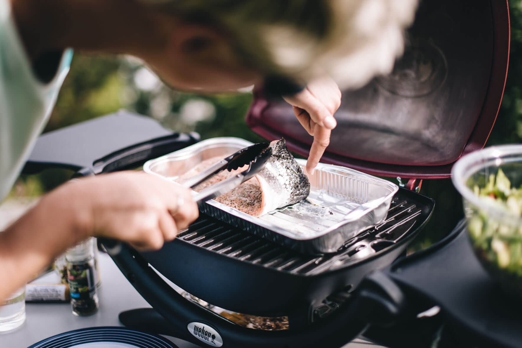 Woman grilling fish on a Weber Q 1200 grill