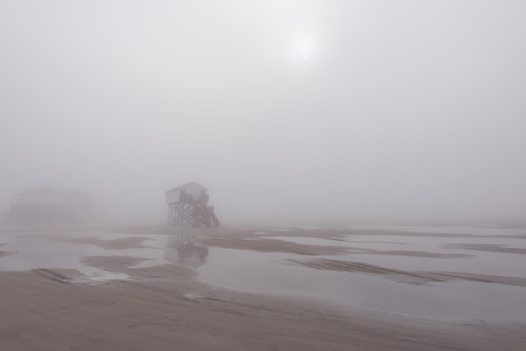 Foggy weather on the beach of St. Peter-Ording with stilt houses